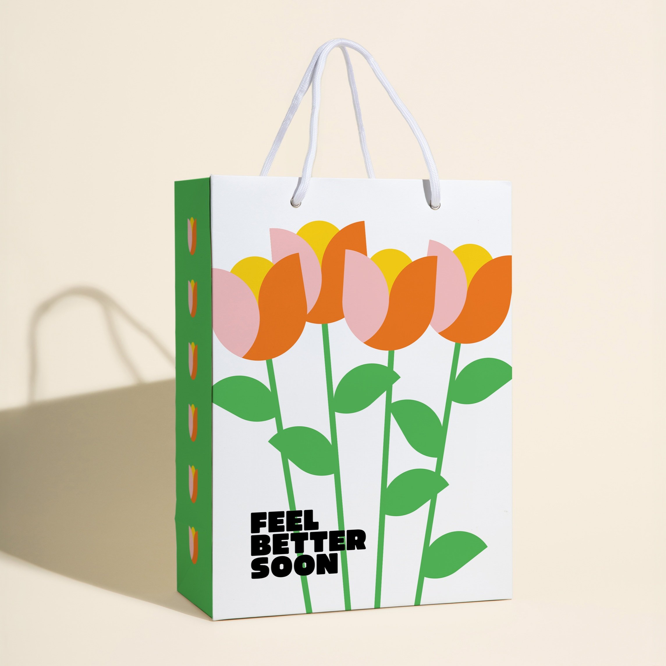 White gift bag with colorful tulip illustrations and the text "feel better soon" in bold black.