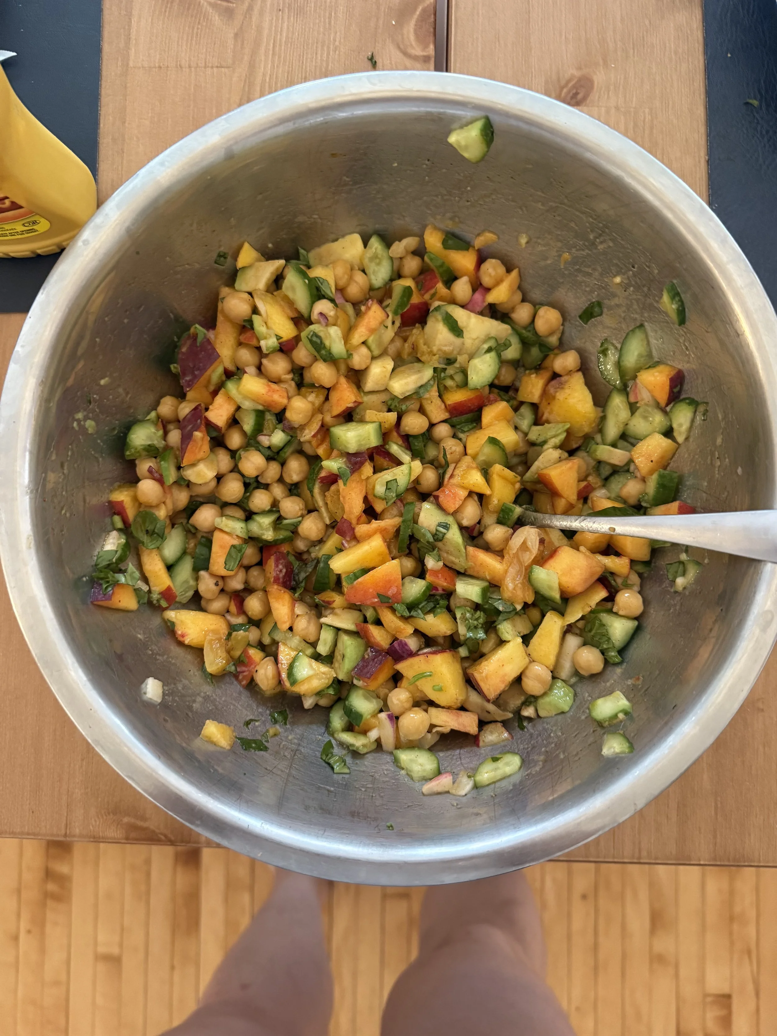 Bowl of chopped cucumbers, bell peppers, chickpeas, and herbs.