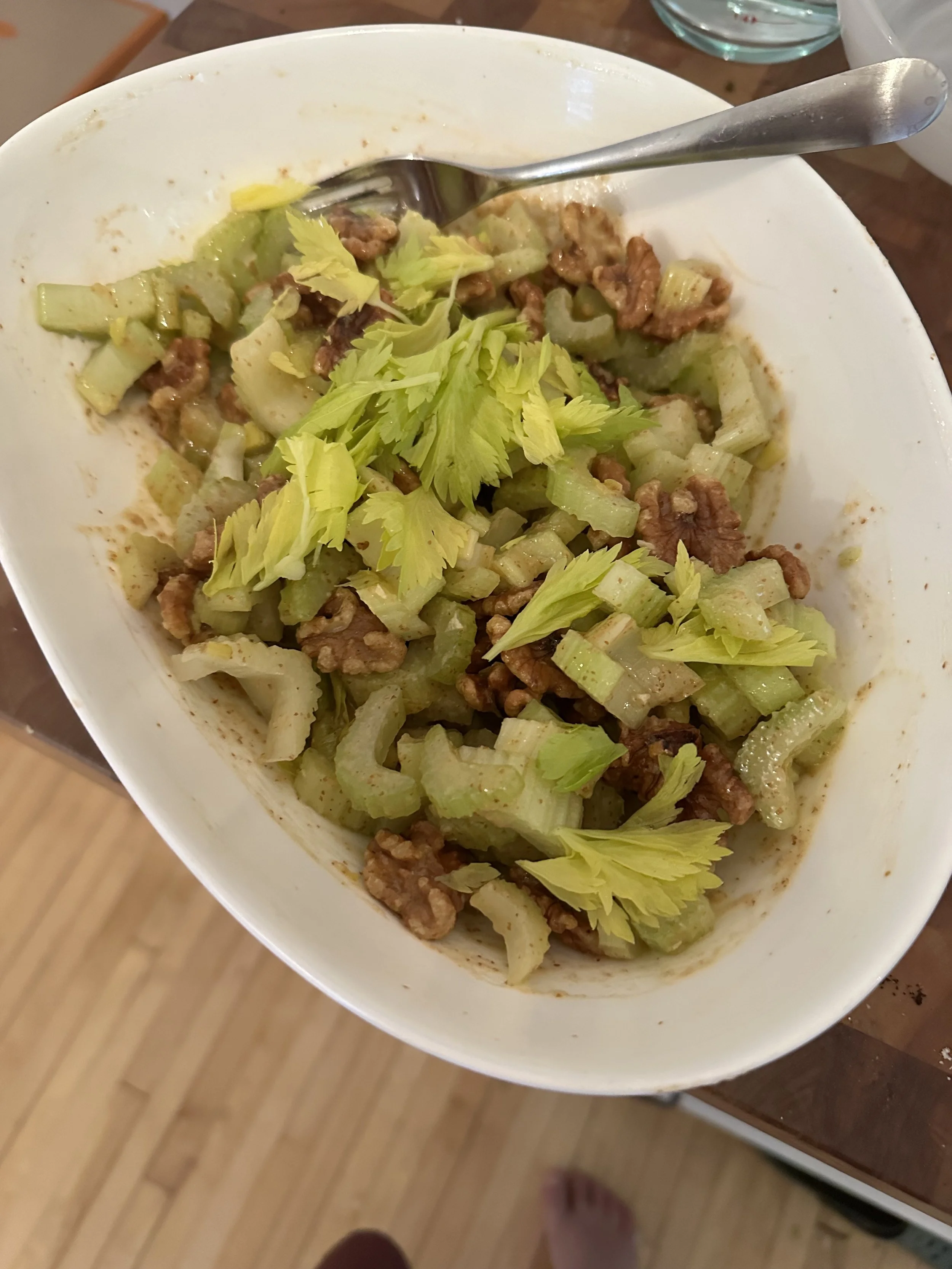 A bowl of cooked celery and ground meat garnished with celery leaves