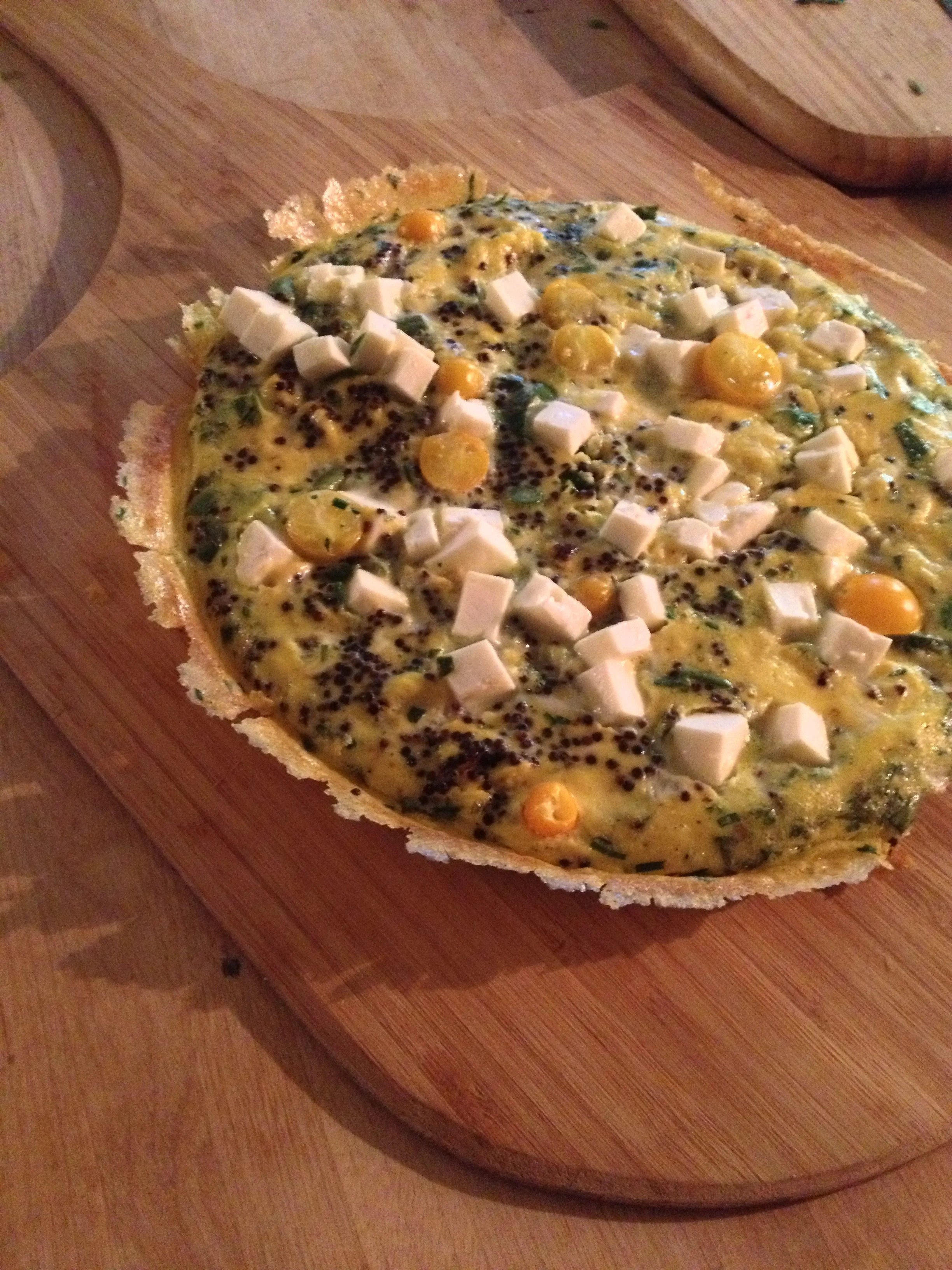Fried egg with chopped cheese, black seeds, and small yellow round toppings served on a wooden cutting board.