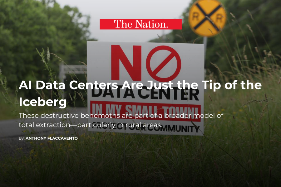 A protest sign on a grassy roadside with a yellow railroad crossing sign in the background. The protest sign has large red and black text and indicates opposition to the construction of an AI data center, mentioning its destructive environmental effects.