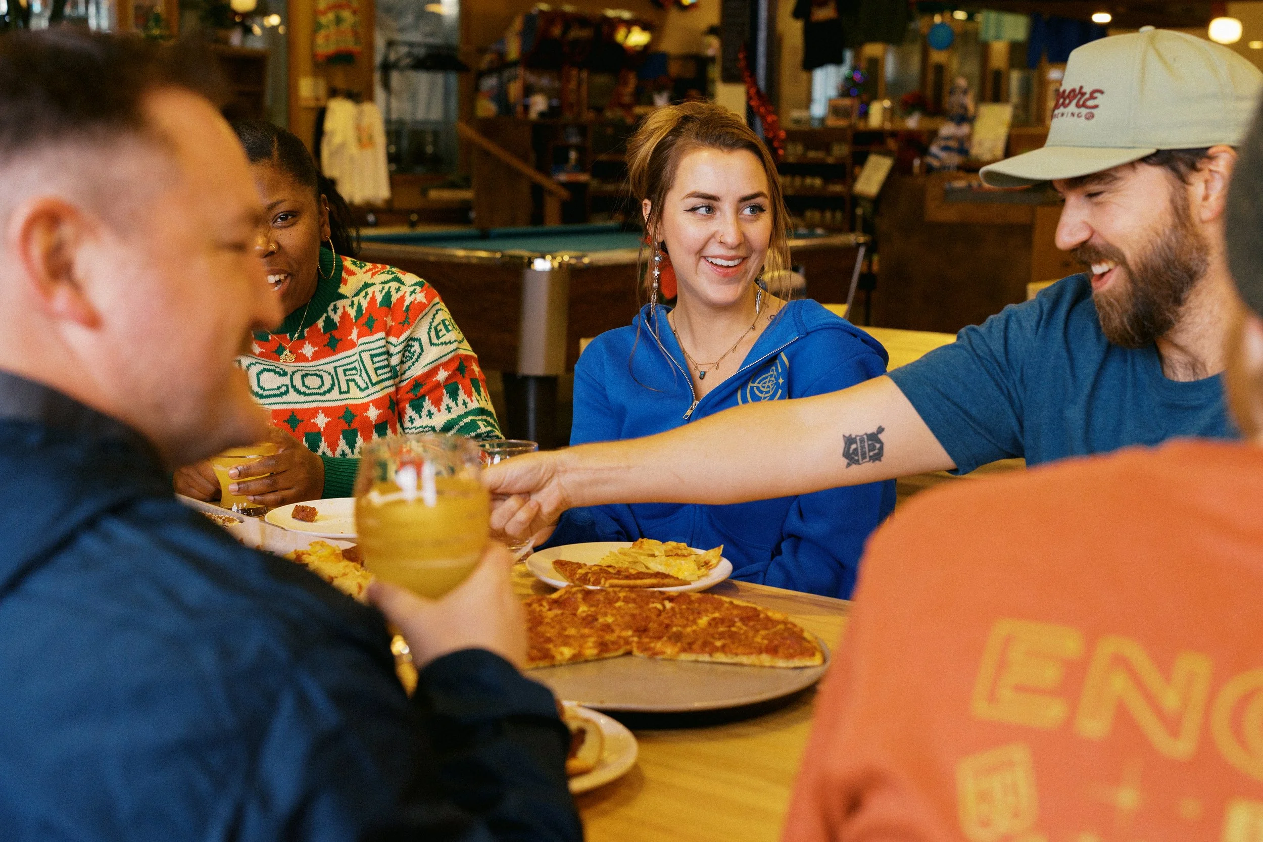 Group of friends enjoying pizza and drinks at a restaurant, smiling and toasting.