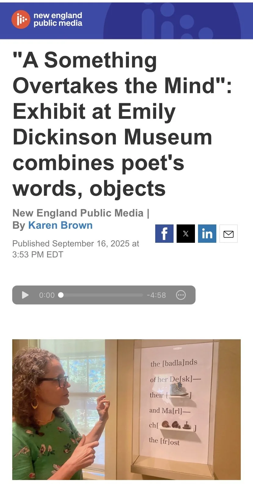 Ligia Bouton pointing at an exhibit display at the Emily Dickinson Museum, which features a poem with words and objects.