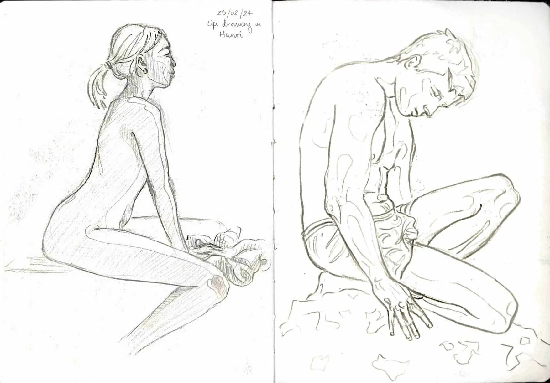 Sketch of a nude woman sitting cross-legged, seen in profile, with her hair tied back, and a nude man sitting cross-legged, also seen in profile, with his head bowed down, on a piece of fabric or cloth on the ground. Text at the top reads "25/02/24 Life drawing in Hanoi."