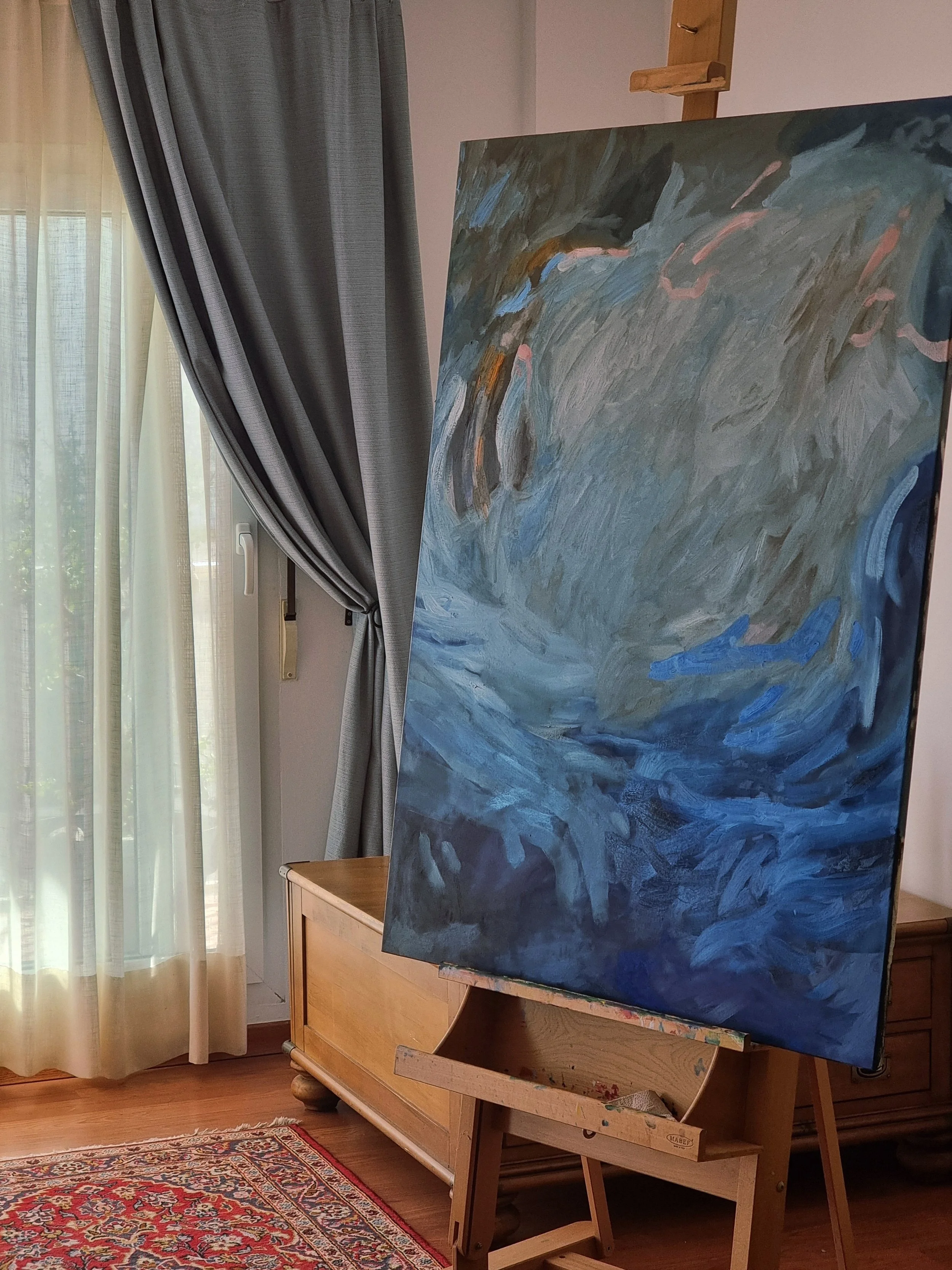 An abstract painting on an easel in a room with curtains, a wooden cabinet, and a patterned rug.