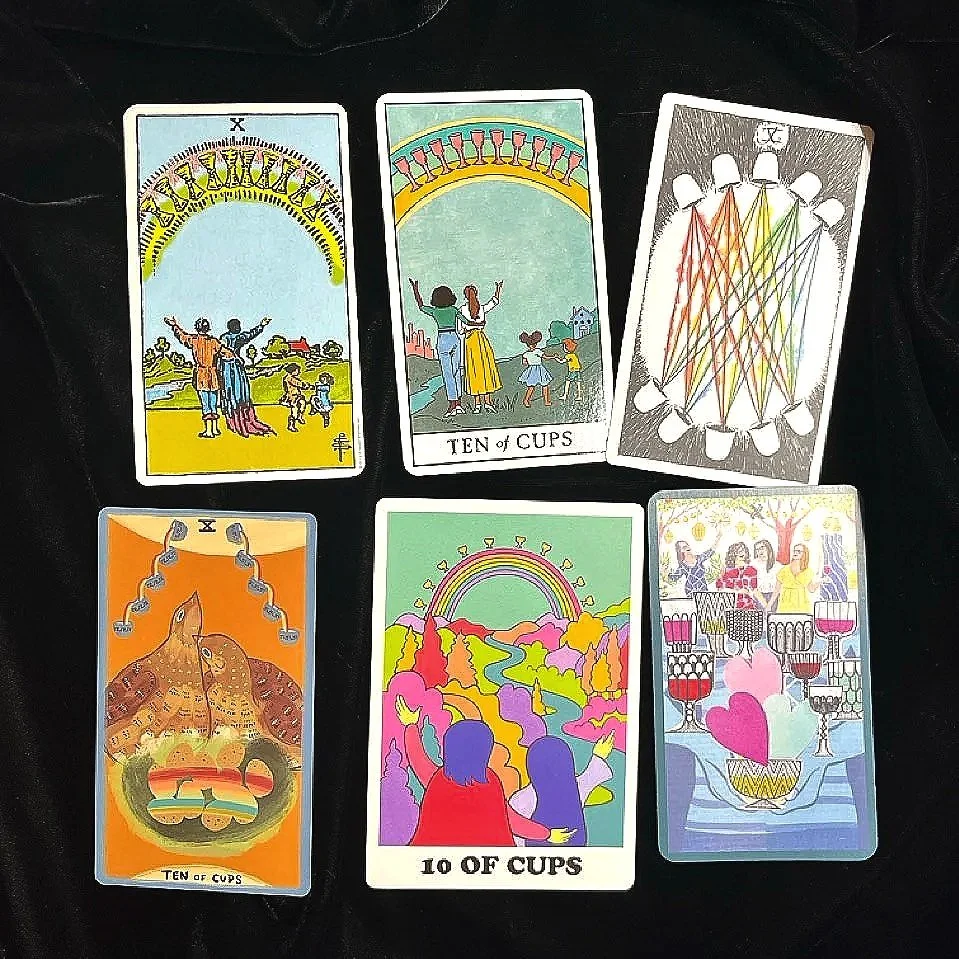 Six different examples of the ten of cups tarot cards, arranged on a black cloth.