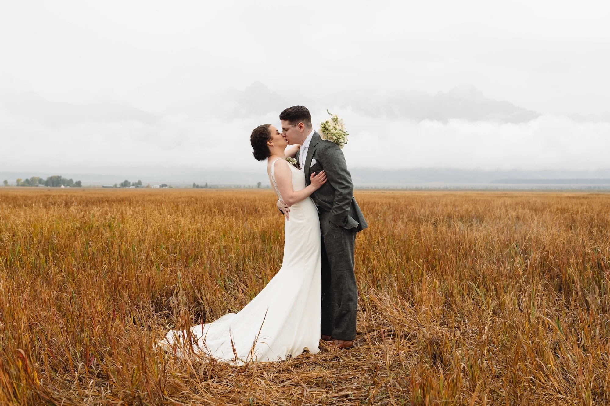 a bride and groom in the rain at mormon row in grand teton