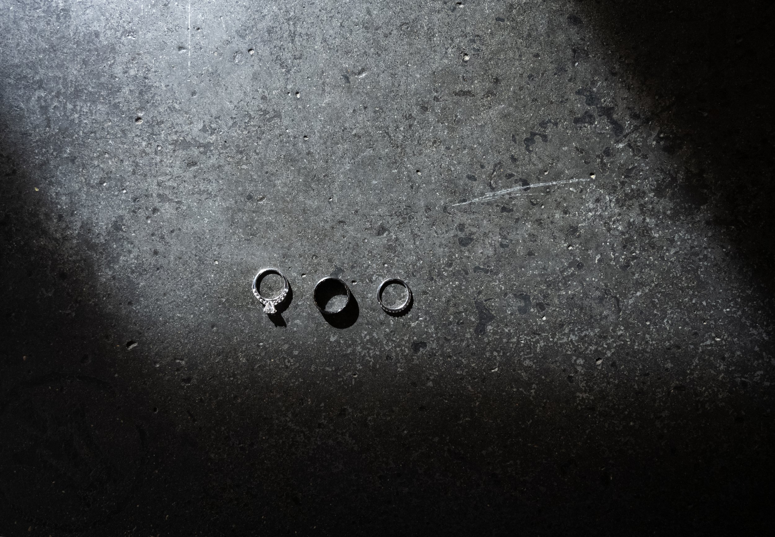 Four rings on a dark, speckled floor, with a shadow cast over part of the image.