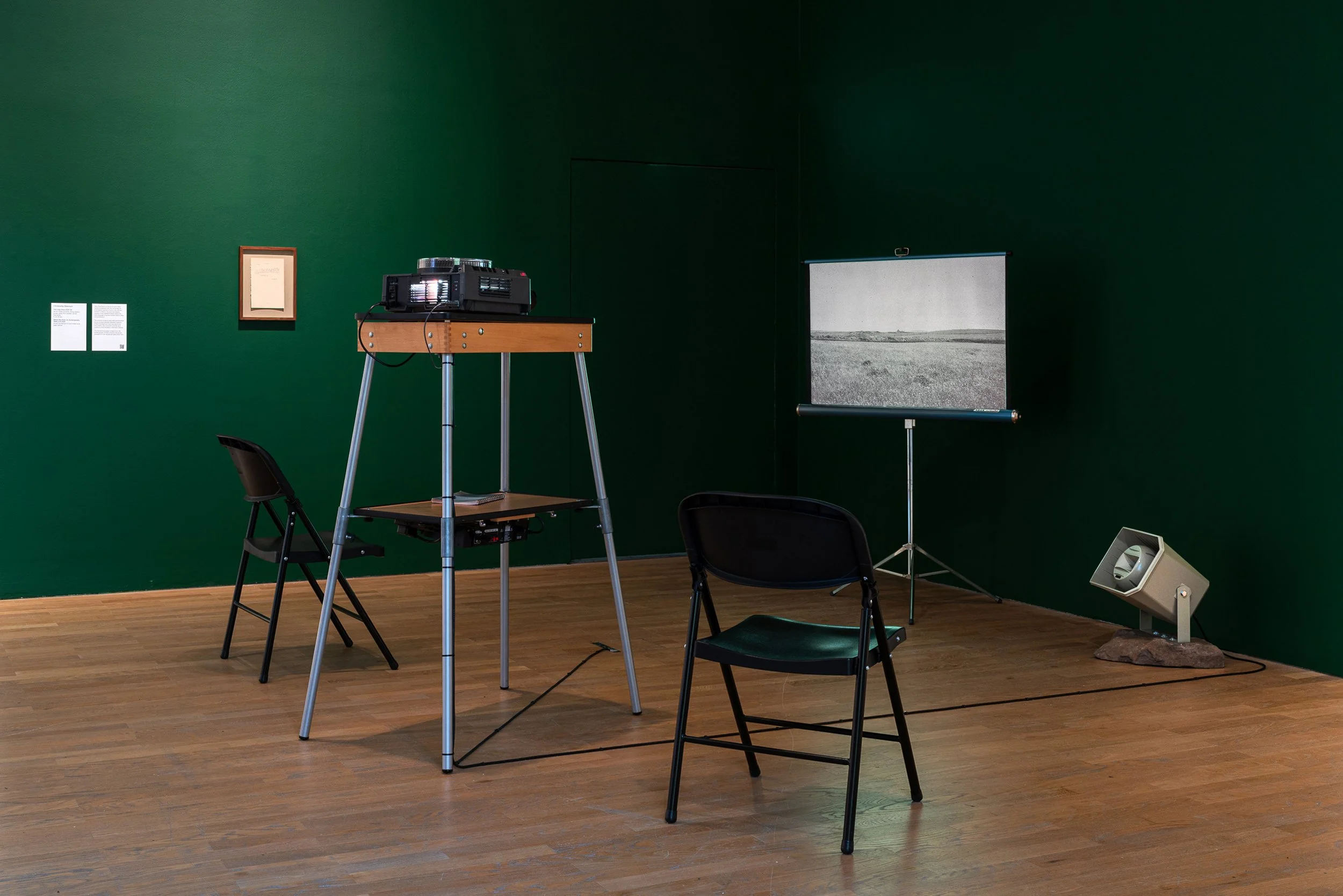 Christopher Steenson,  The Long Grass , 2022–24, 35mm slides, slide projector, vintage portable projection screen and projection table, timing system, amplifier, horn speaker, carved field stone, cabling. Dimensions variable. Duration: 5 minutes 49 s