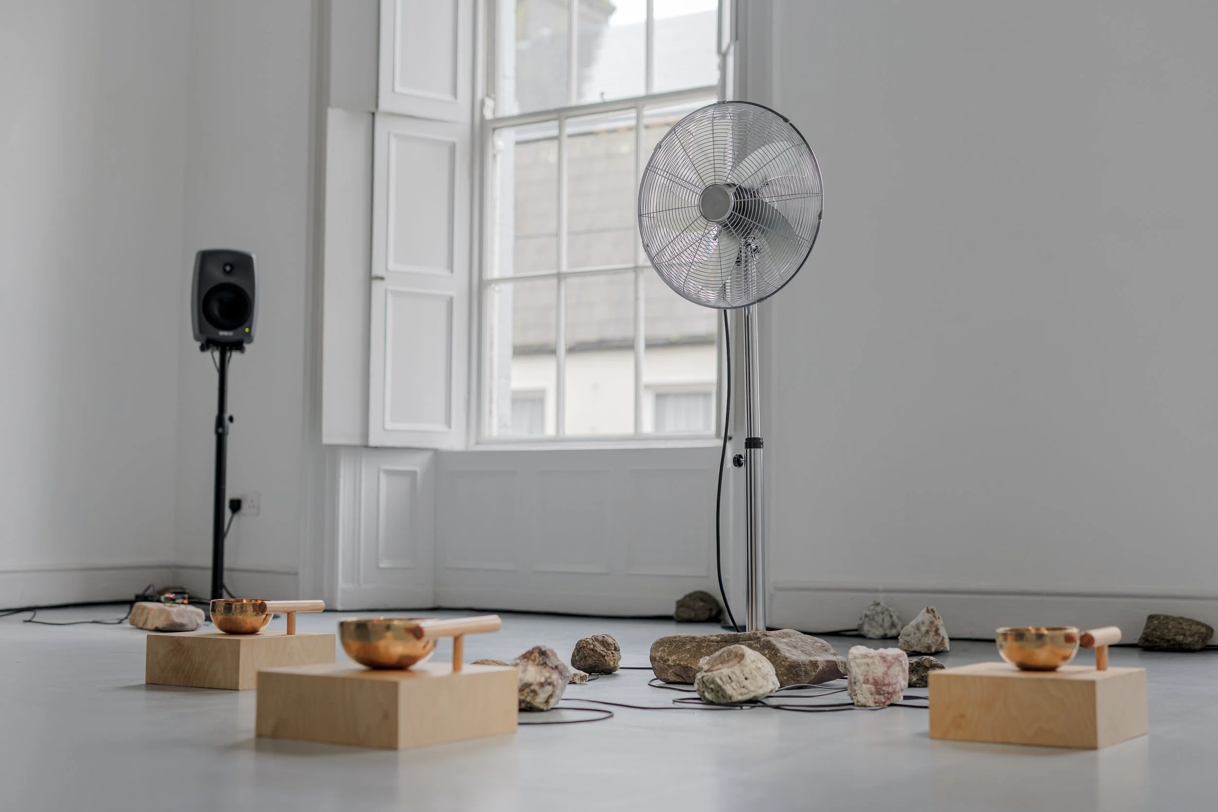  Where Does the Body End? , 2025, air quality sensor, singing bowls, chrome-plated pedestal fan, wood, carved stone, 3D-printed components, five-channel sound, custom software, Raspberry Pi microcomputers, Arduino microcontrollers, motors, circuitry,
