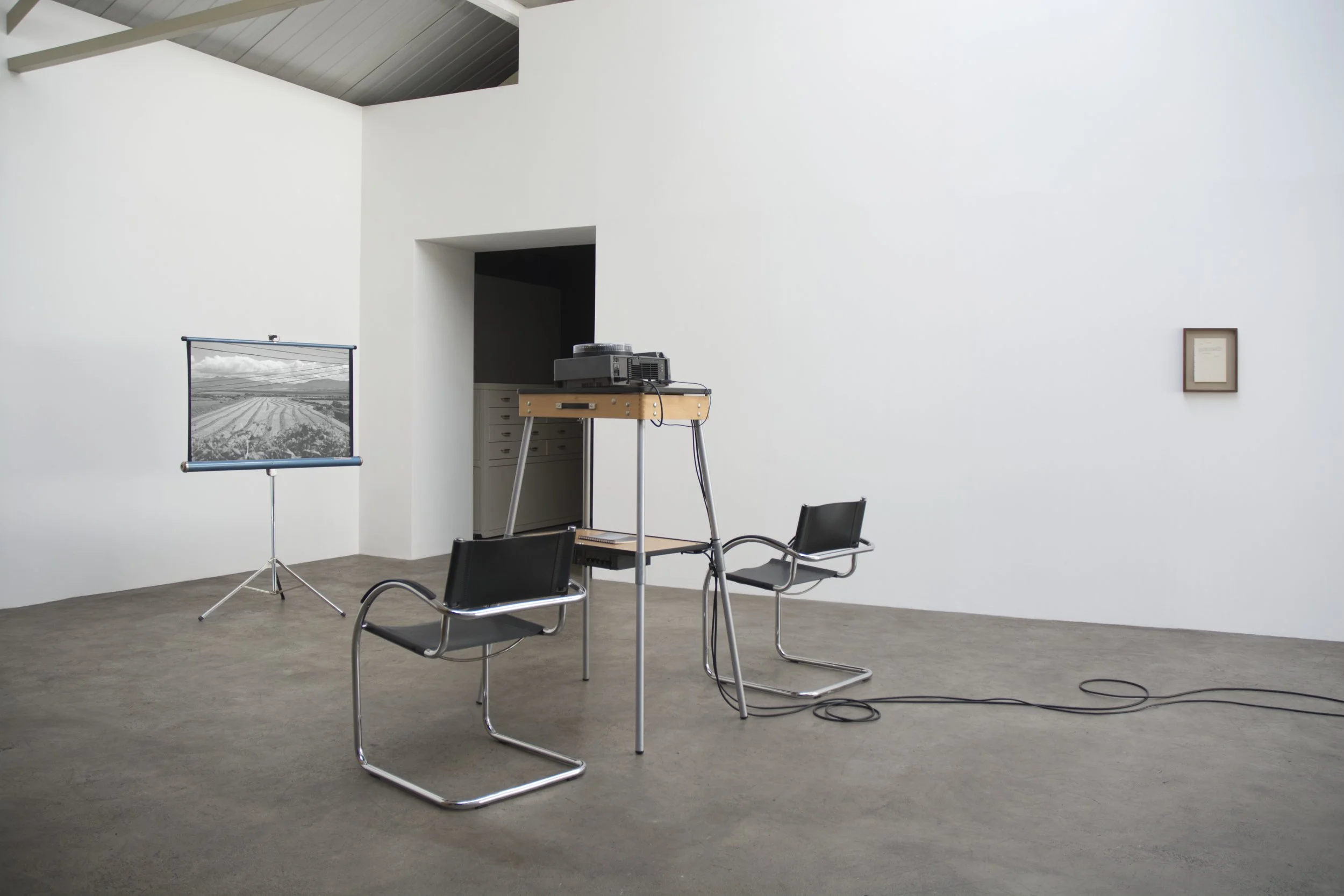 Christopher Steenson,  The Long Grass , 2022–24, 35mm slides, slide projector, vintage portable projection screen and projection table, timing system, amplifier, horn speaker, carved field stone, cabling. Dimensions variable. Duration: 5 minutes 49 s