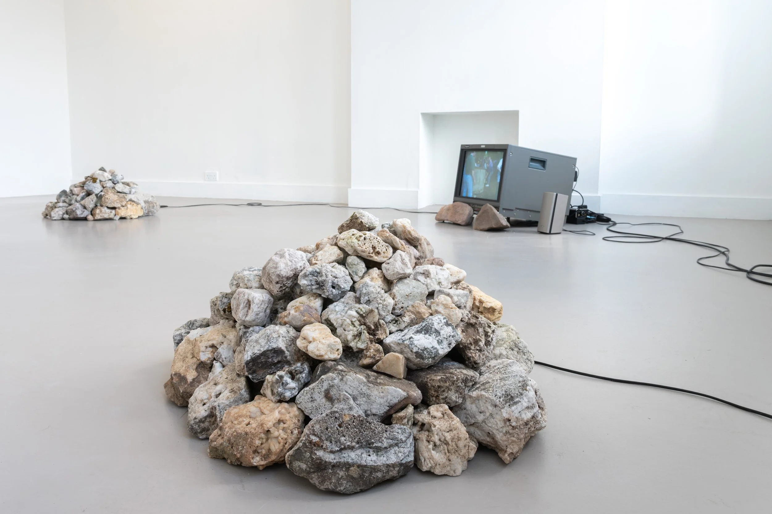 Vinny Cunningham,  Moving Border Bollards , 1994, HD, colour, stereo sound. Duration: 4 min 38 sec (looped), with 
Christopher Steenson,  The Movers , 2026, four-channel spatial sound, voices of collaborators, hand-collected rock quartz, speakers, st