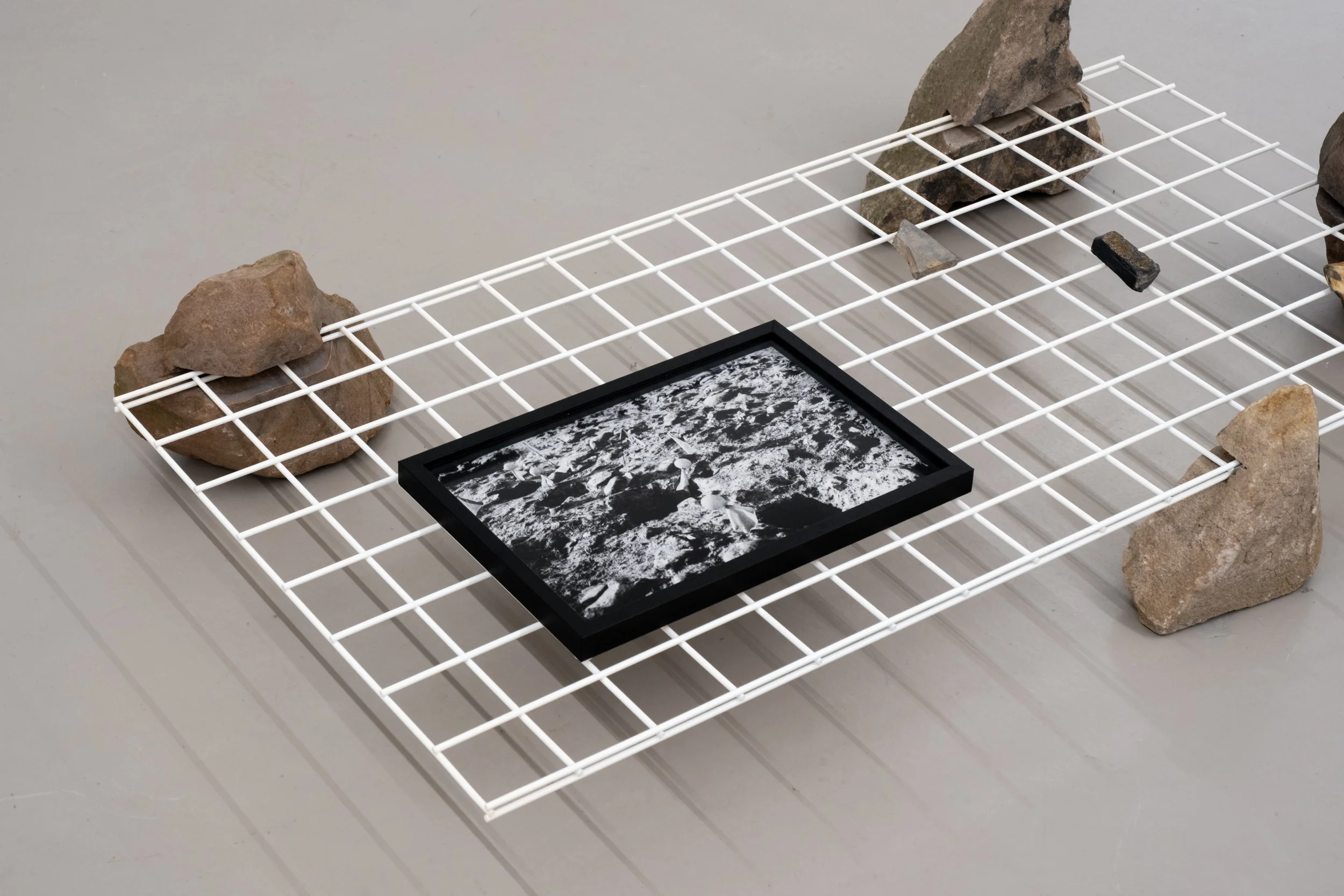 Christopher Steenson,  Cnocán an Chuig (postholes) , 2026, pigment print on archival photo paper, 38 x 25.3 cm (unframed). Edition of 3 + 1AP; carved field stones, powder-coated steel grid. Photo: Christopher Steenson. 