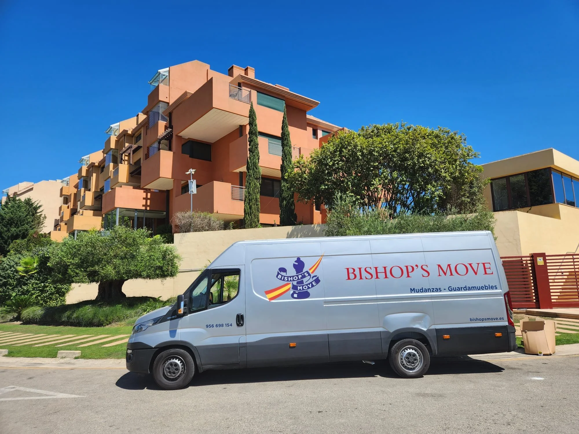 A silver Bishop's Move removals van parked in a residential driveway, ready for a UK to Spain move.