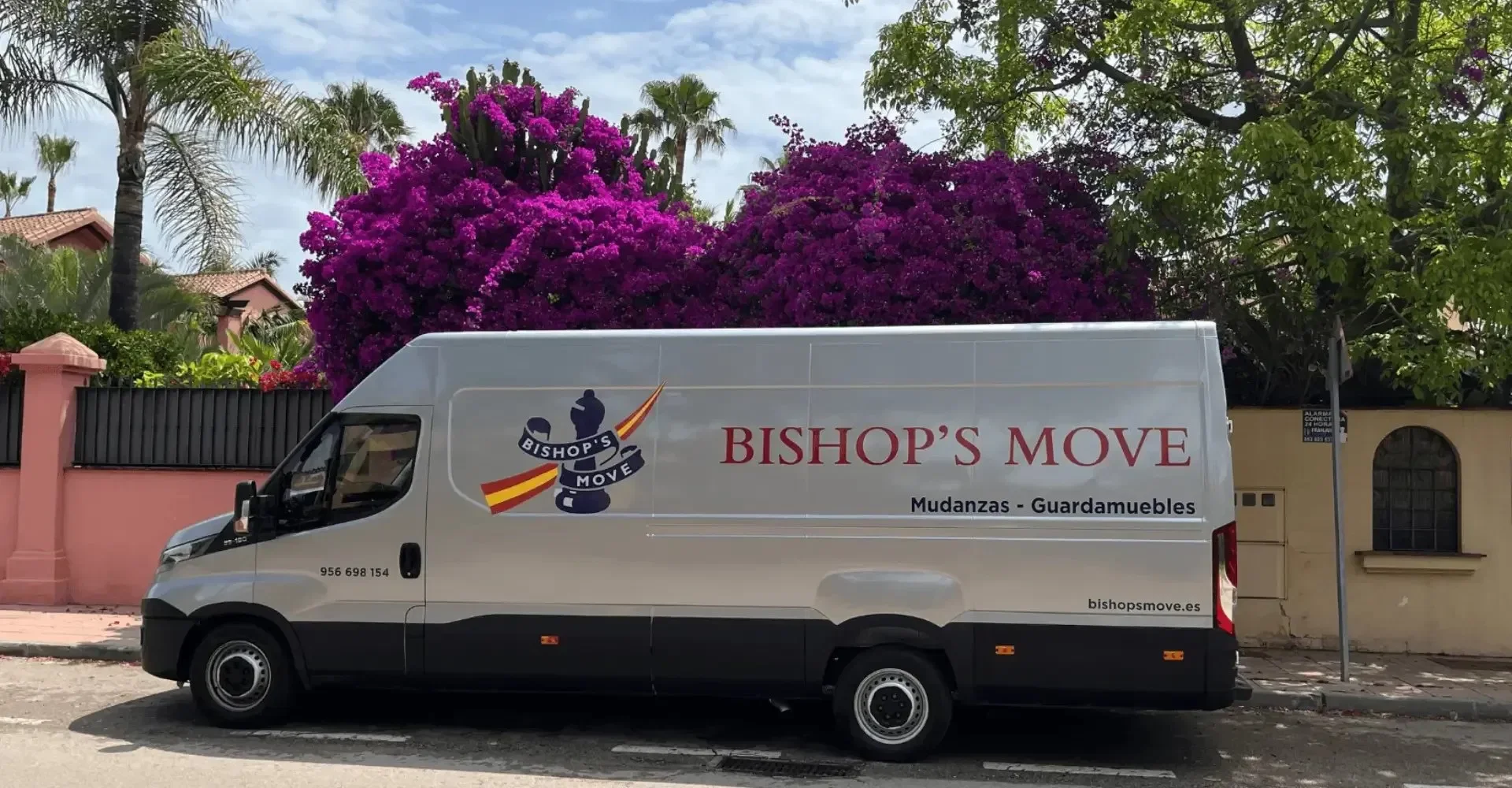 A Bishop's Move van parked outside a premium villa in Marbella, surrounded by palm trees.