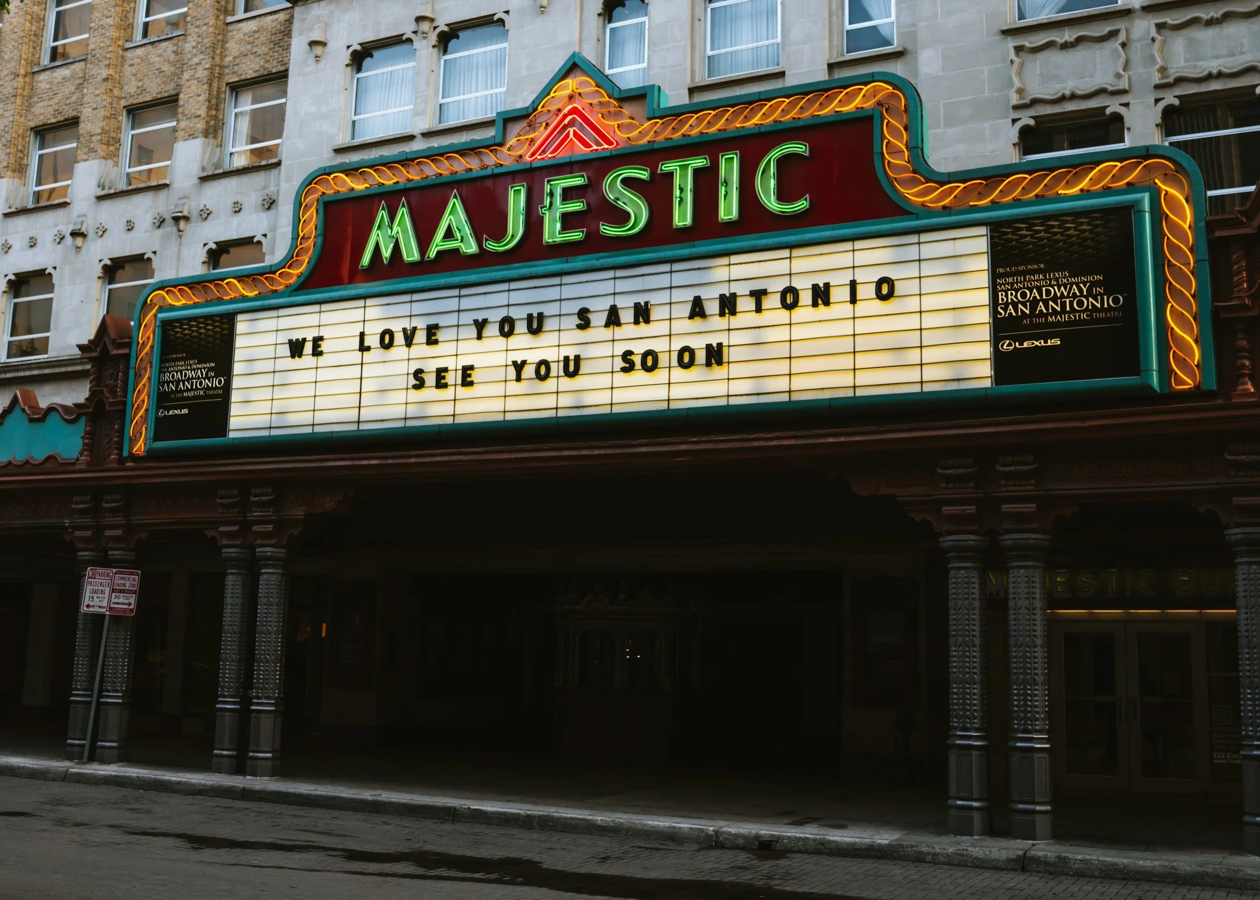 Marquee sign for Majestic Theatre with message: "We love you San Antonio. See you soon." The sign is in front of a vintage brick and stone building with windows.
