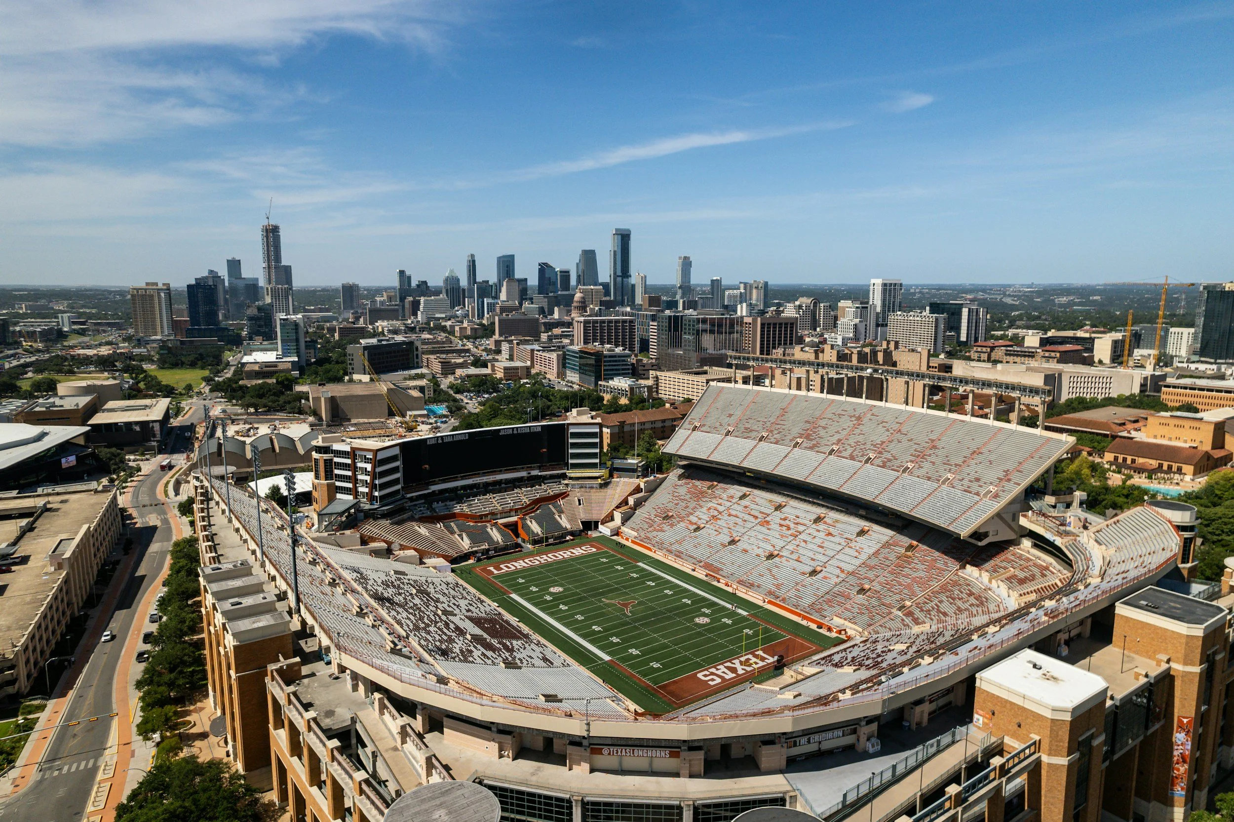 A city skyline with tall skyscrapers and a football stadium in the foreground, during daytime with clear blue skies.