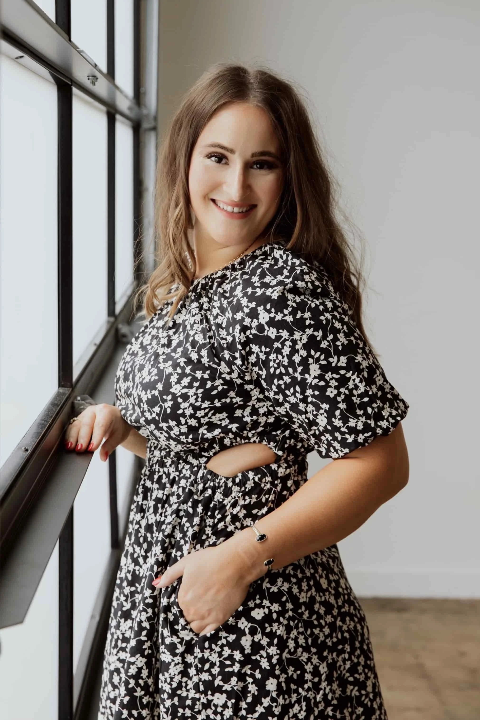 Woman dressed professionally in a black and white floral dress expressing her kindness and presentation for therapy sessions | Relationship and Trauma Therapist in Texas | Sport Performance Therapist | Dallas Texas