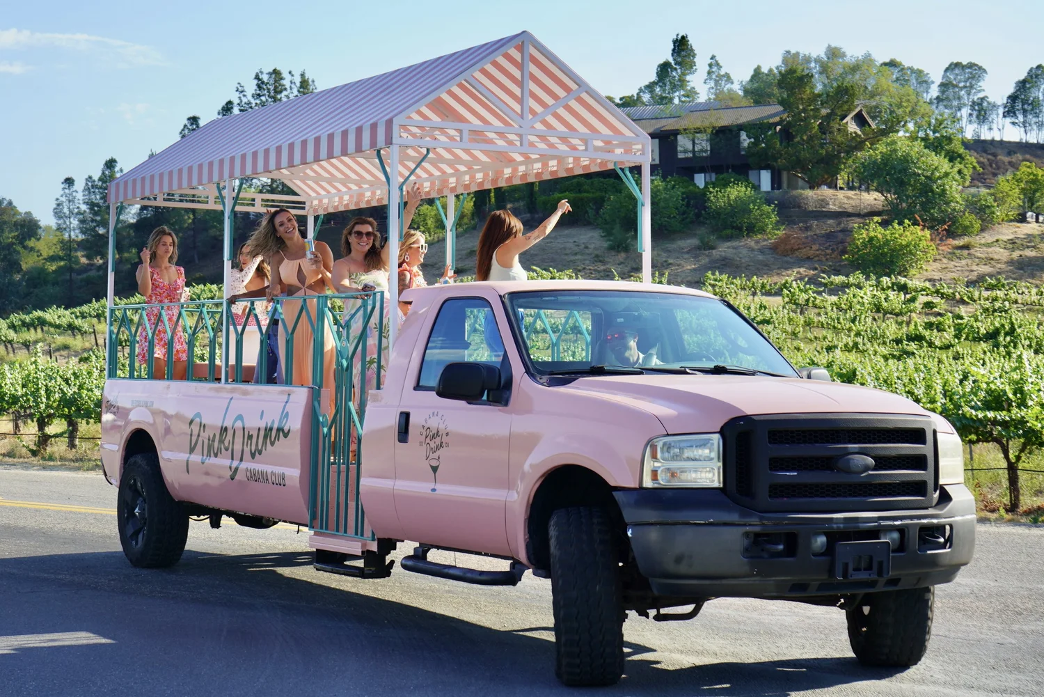 Guests riding through the vineyard aboard Pink Drink, our pink open-air cabana truck.