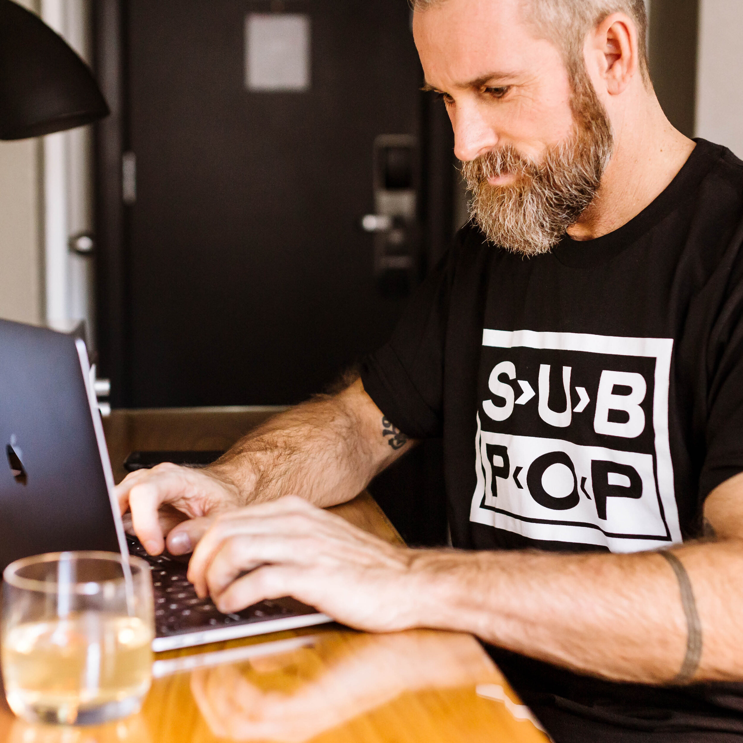 Ryan Hodgson working at a laptop at a wooden table.