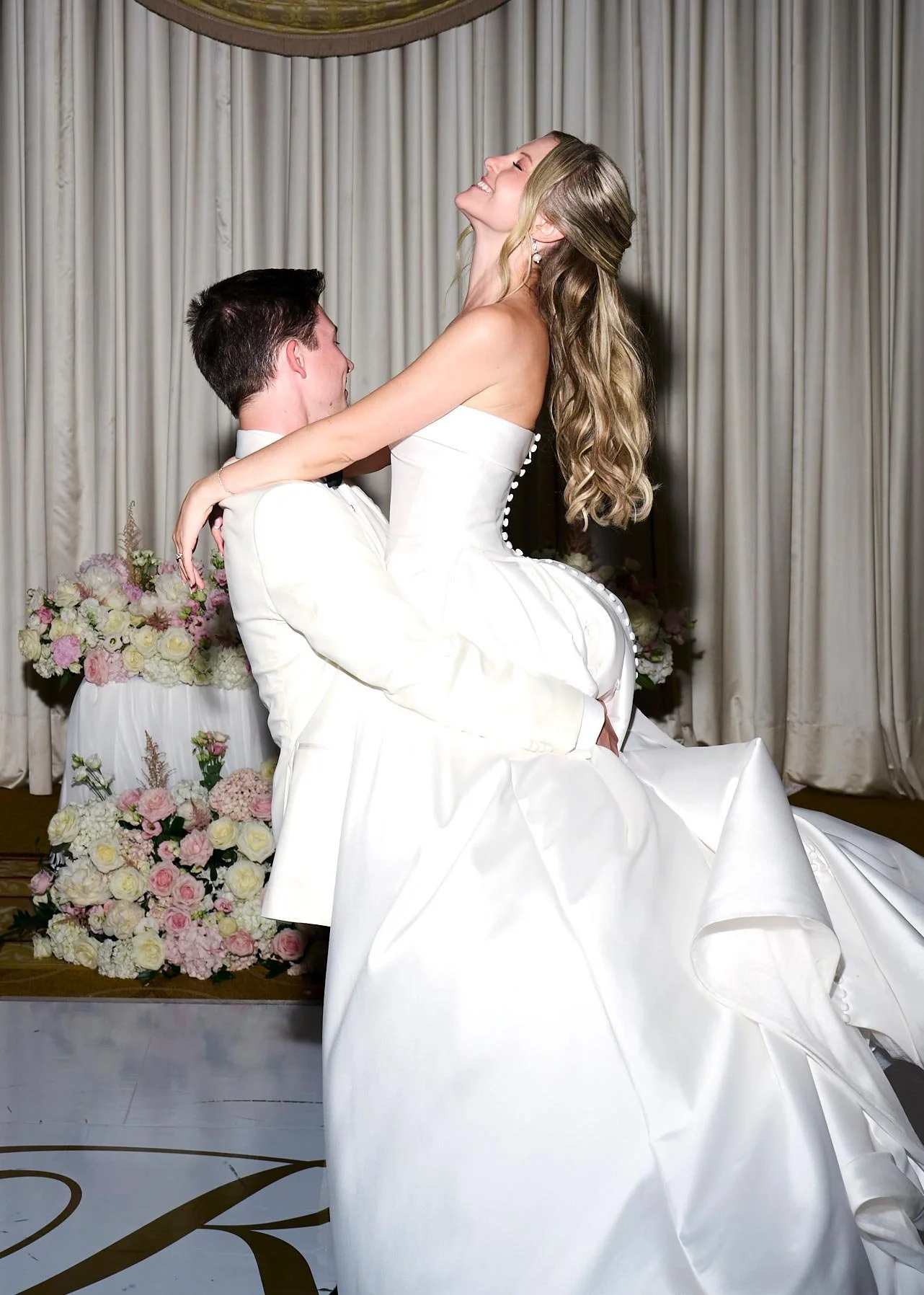 Image 4 — Marié portant la mariée devant des rideaux