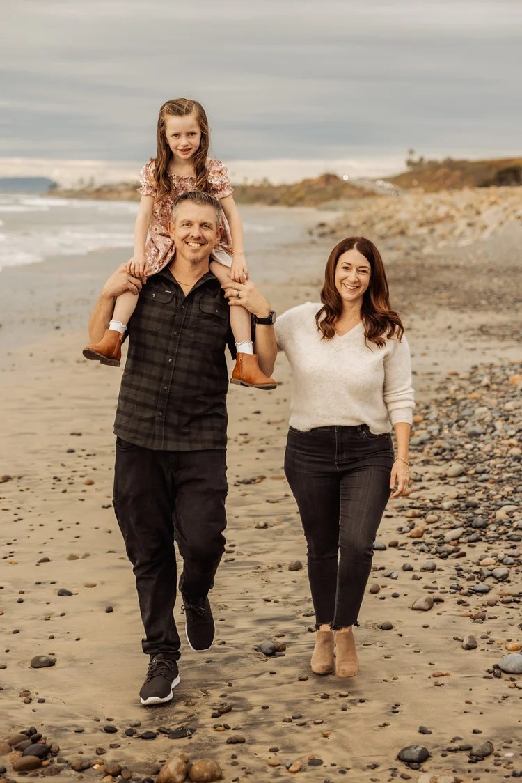 Family walking the cobble shoreline below the bluffs in Carlsbad, San Diego County