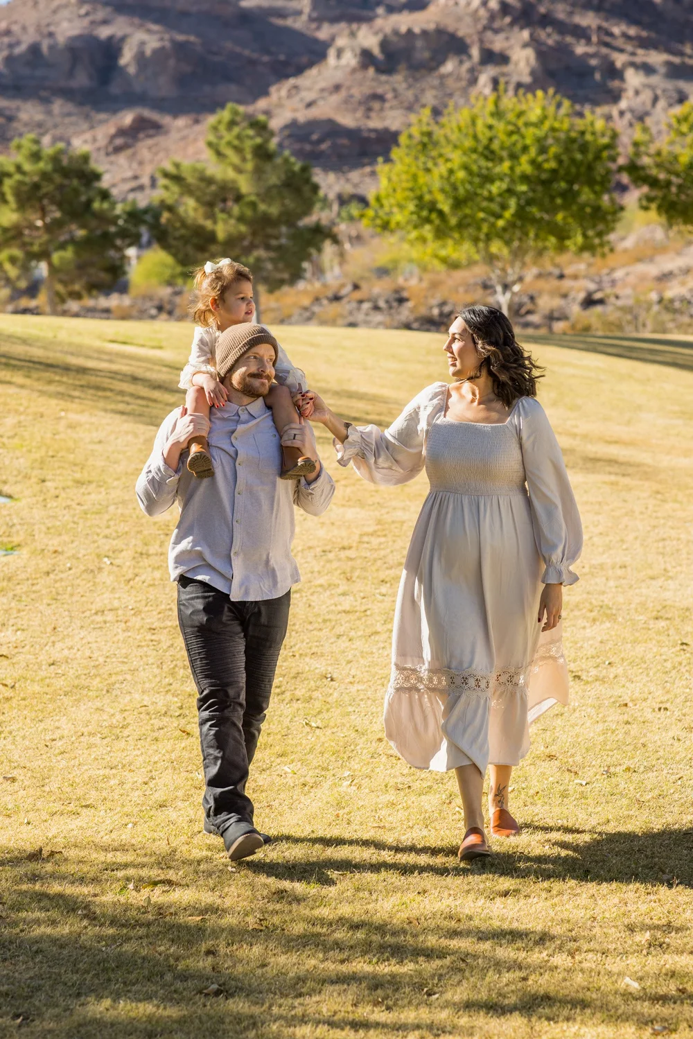 Mother and daughters walking through an open field during a Henderson family session