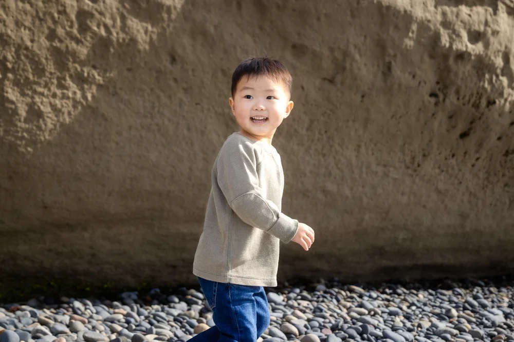 Child in a blue dress photographed in motion on a sandy beach