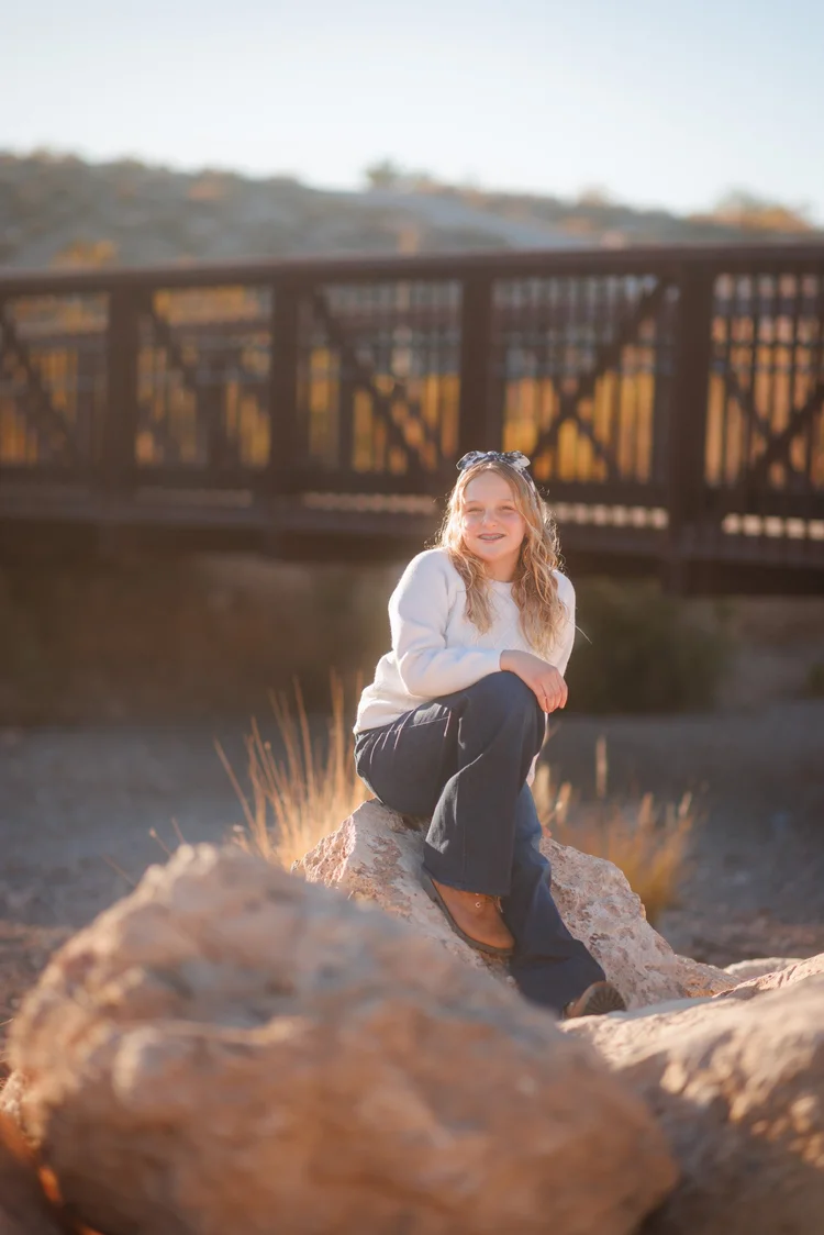 Las Vegas kids photographer, girl sitting beside a wooden bridge in Summerlin