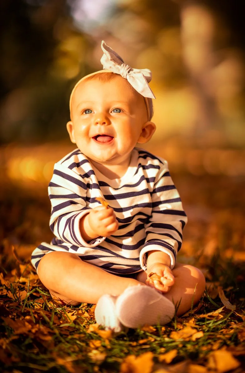 Smiling baby sitting in autumn leaves during a Las Vegas portrait session
