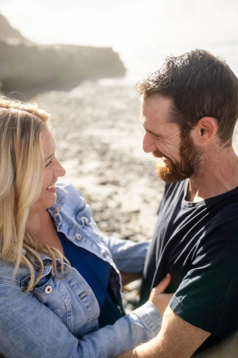 Couple smiling together during a relaxed beach engagement session