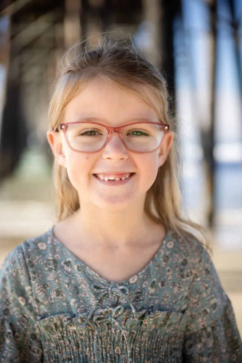 Girl with glasses smiling during an outdoor child portrait session