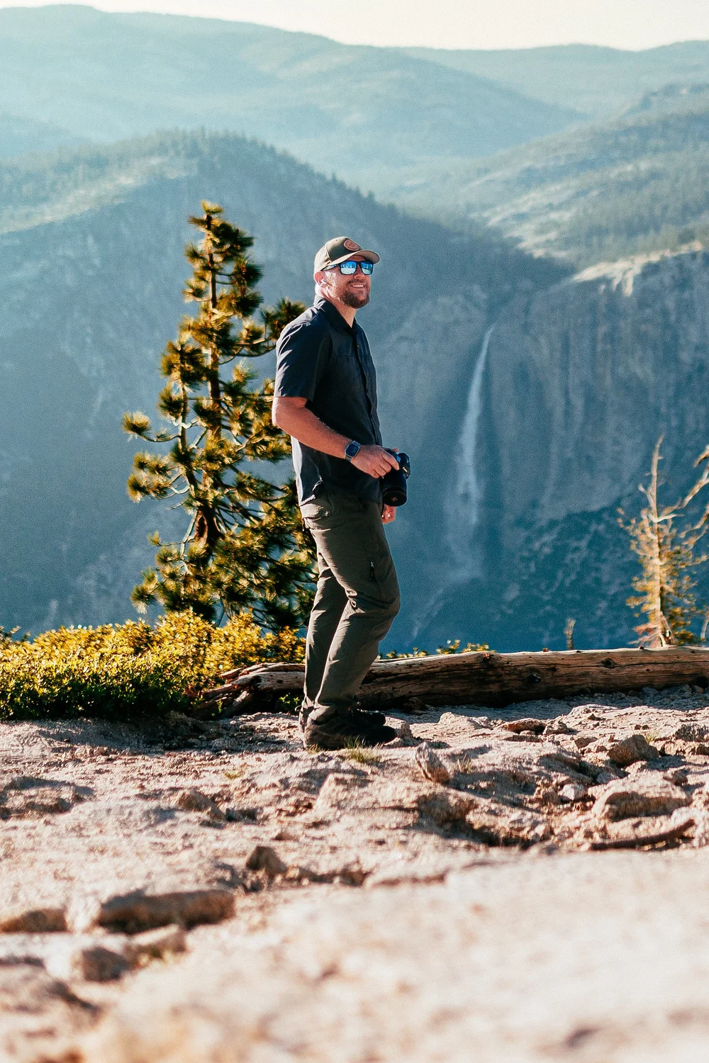 Joseph with a camera on a granite overlook above a waterfall