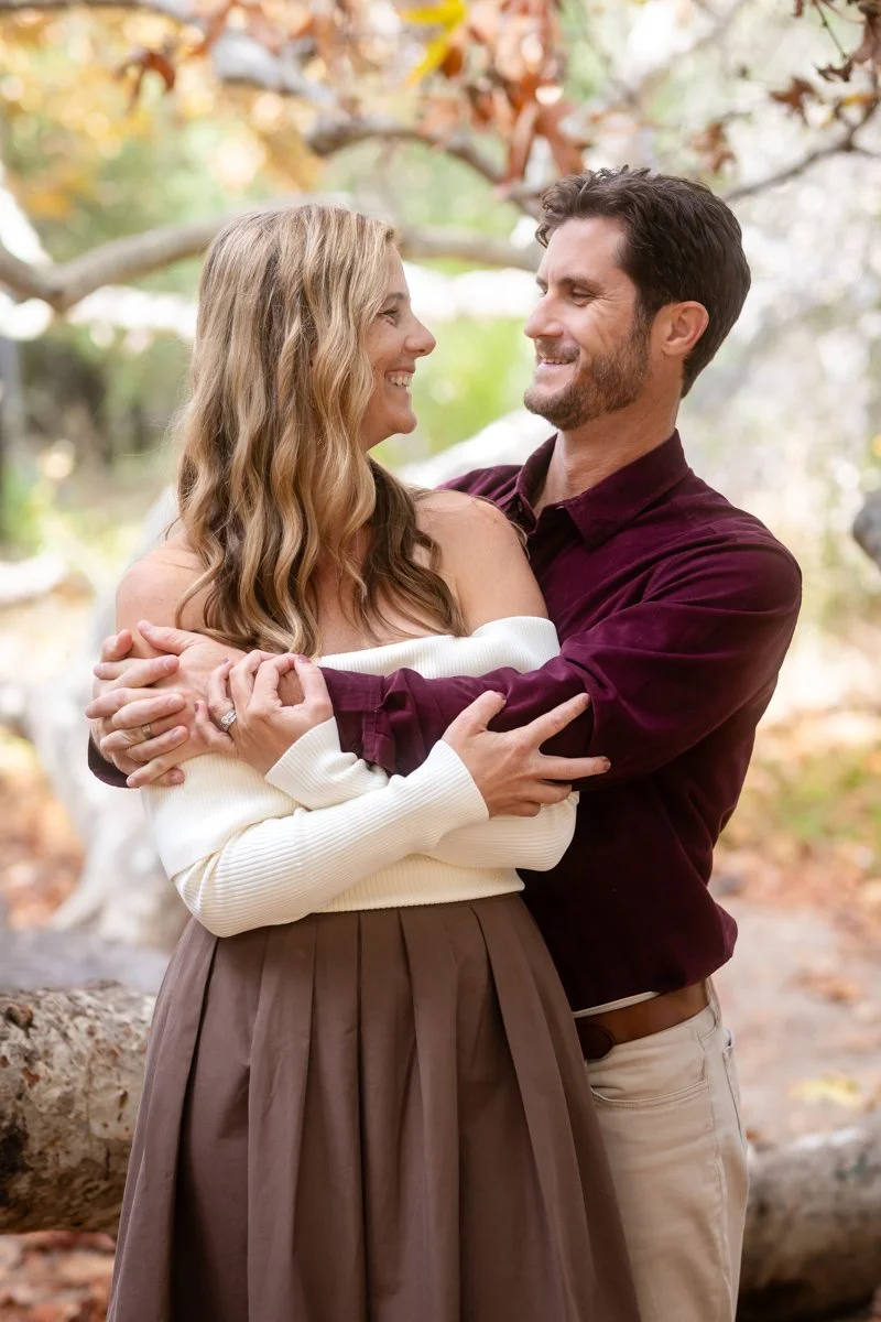 Engaged couple embracing outdoors in soft natural light