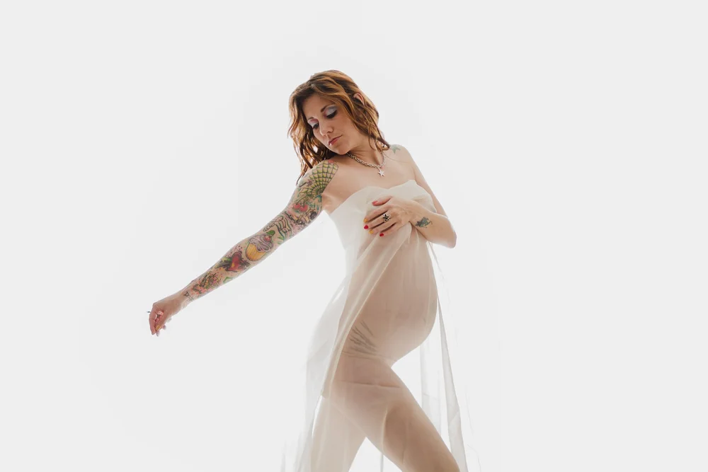 High-key Las Vegas boudoir maternity portrait in a sheer white wrap