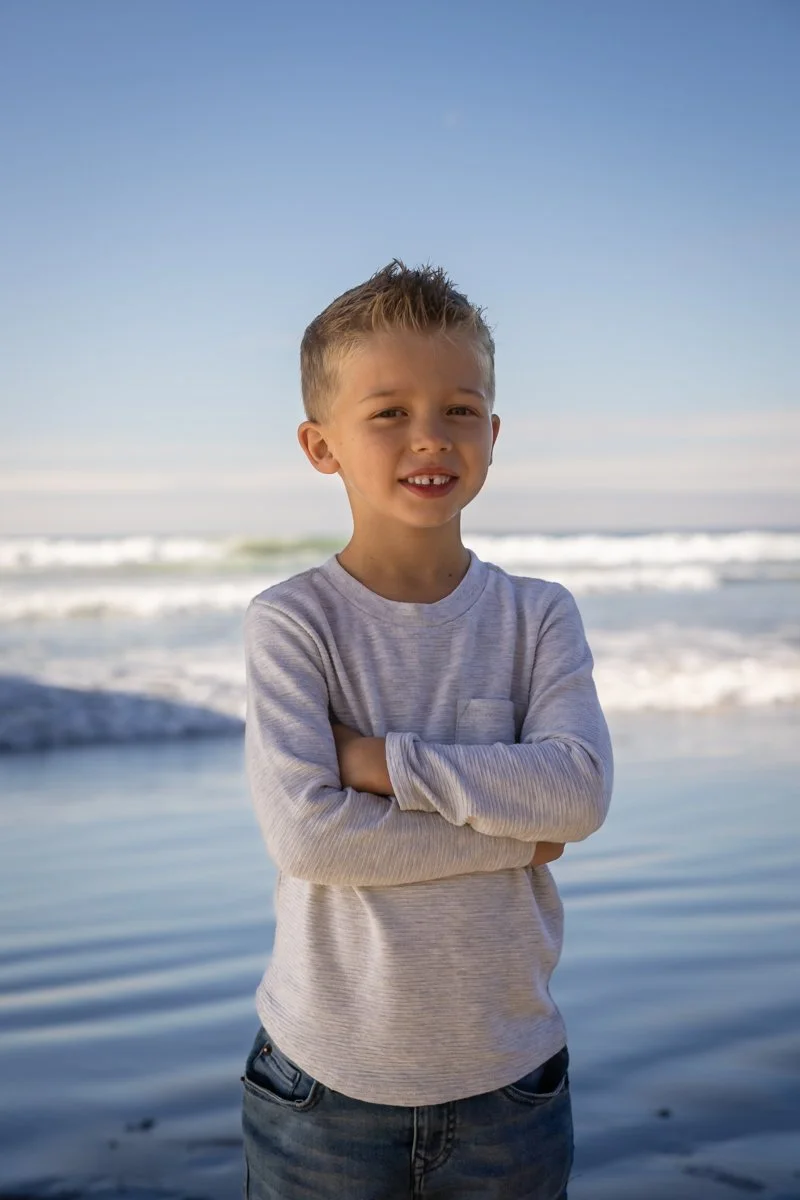 Young boy standing confidently at the beach during a portrait session