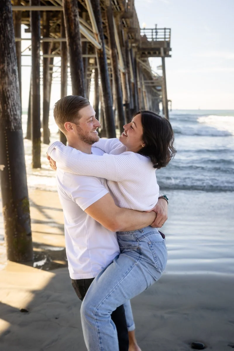Couple embracing beside the ocean during an engagement photography session
