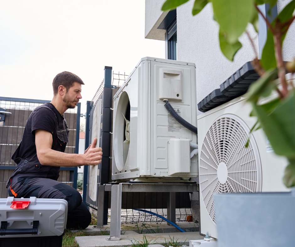 A technician repairing an outdoor air conditioning unit on the house exterior.