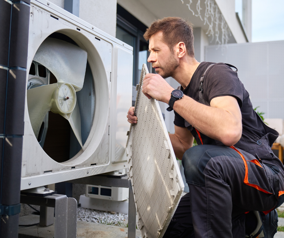 A technician inspecting the internal components of a washing machine outdoors.