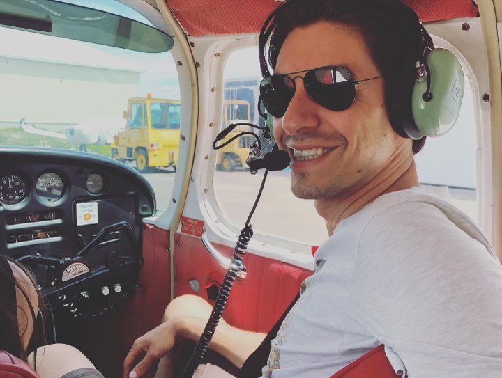 Man smiling with sunglasses on in plane