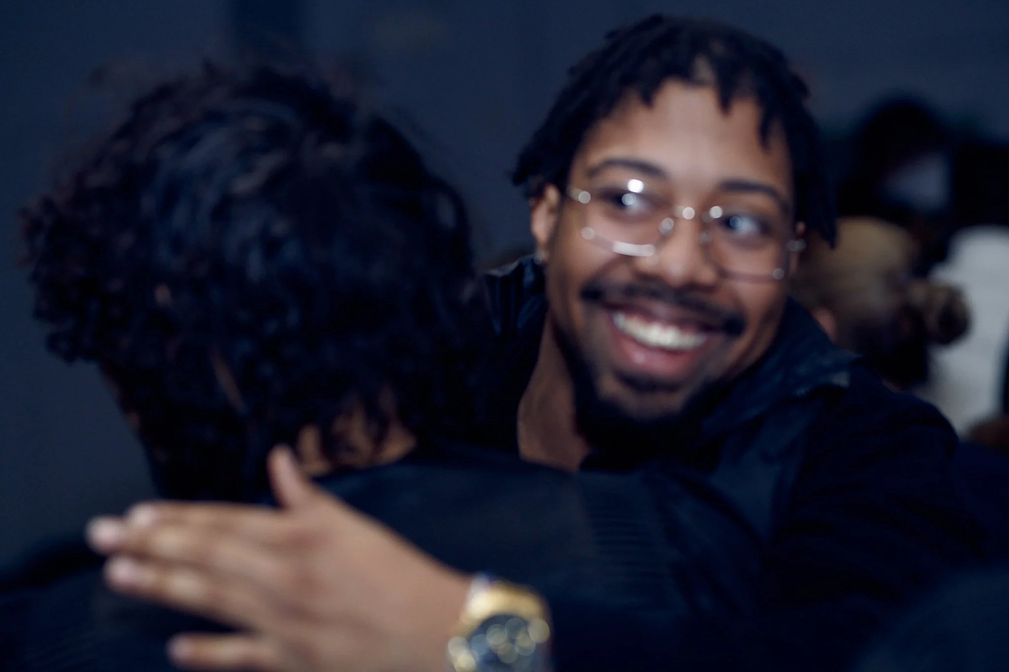 Deux personnes s'étreignent, l'une souriante, dans une ambiance chaleureuse.