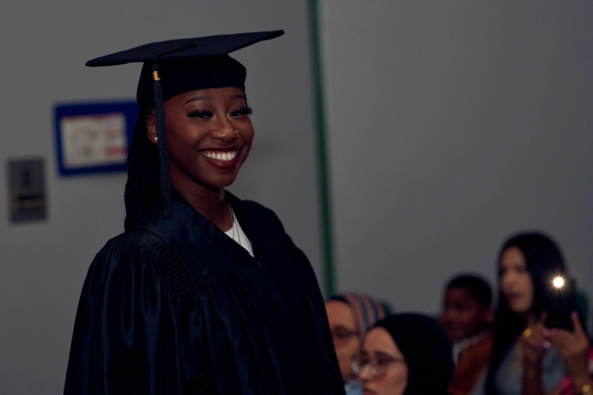 Femme souriante en robe de graduation et mortier lors de la cérémonie.