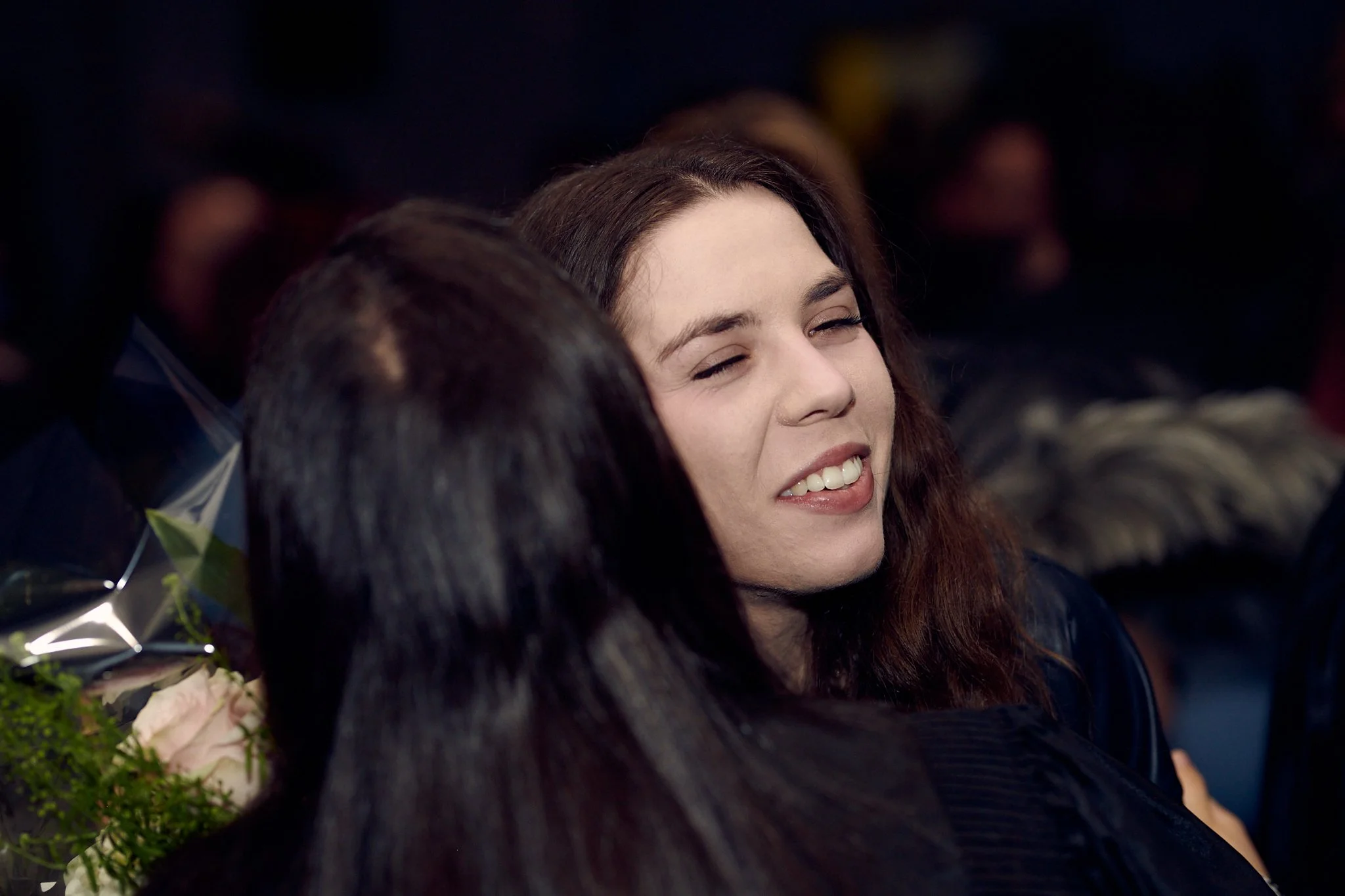 Une jeune femme souriante reçu un câlin lors d'une célébration ou d'un événement social.