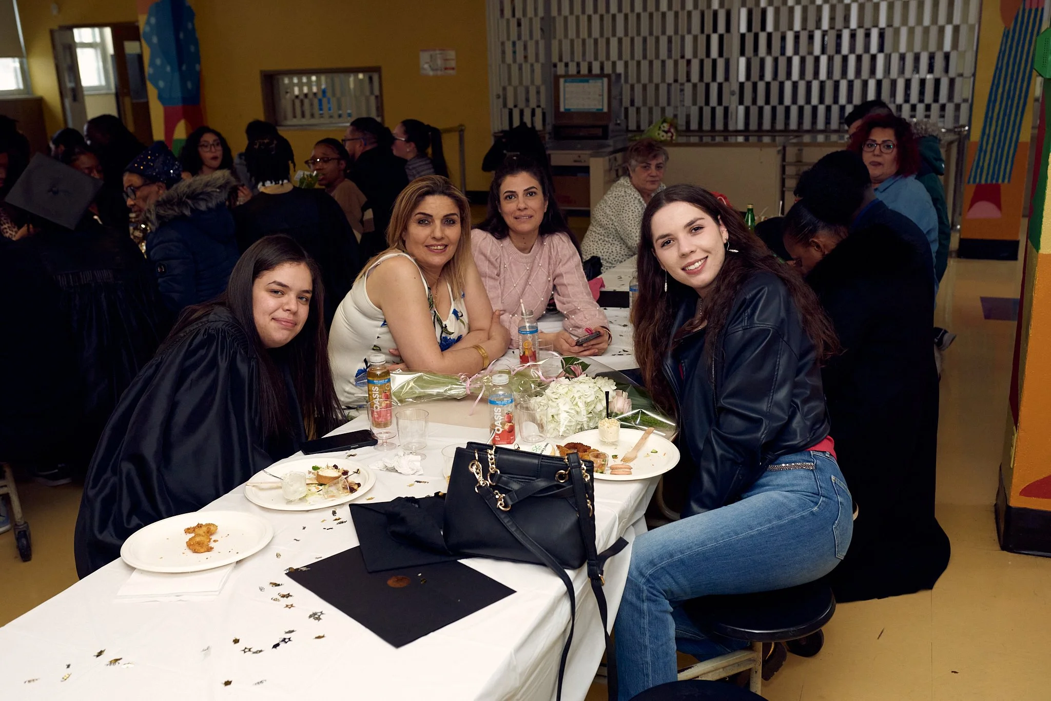 Groupe de femmes assises autour d'une table lors d'une célébration ou d'une fête, mangeant et souriant.