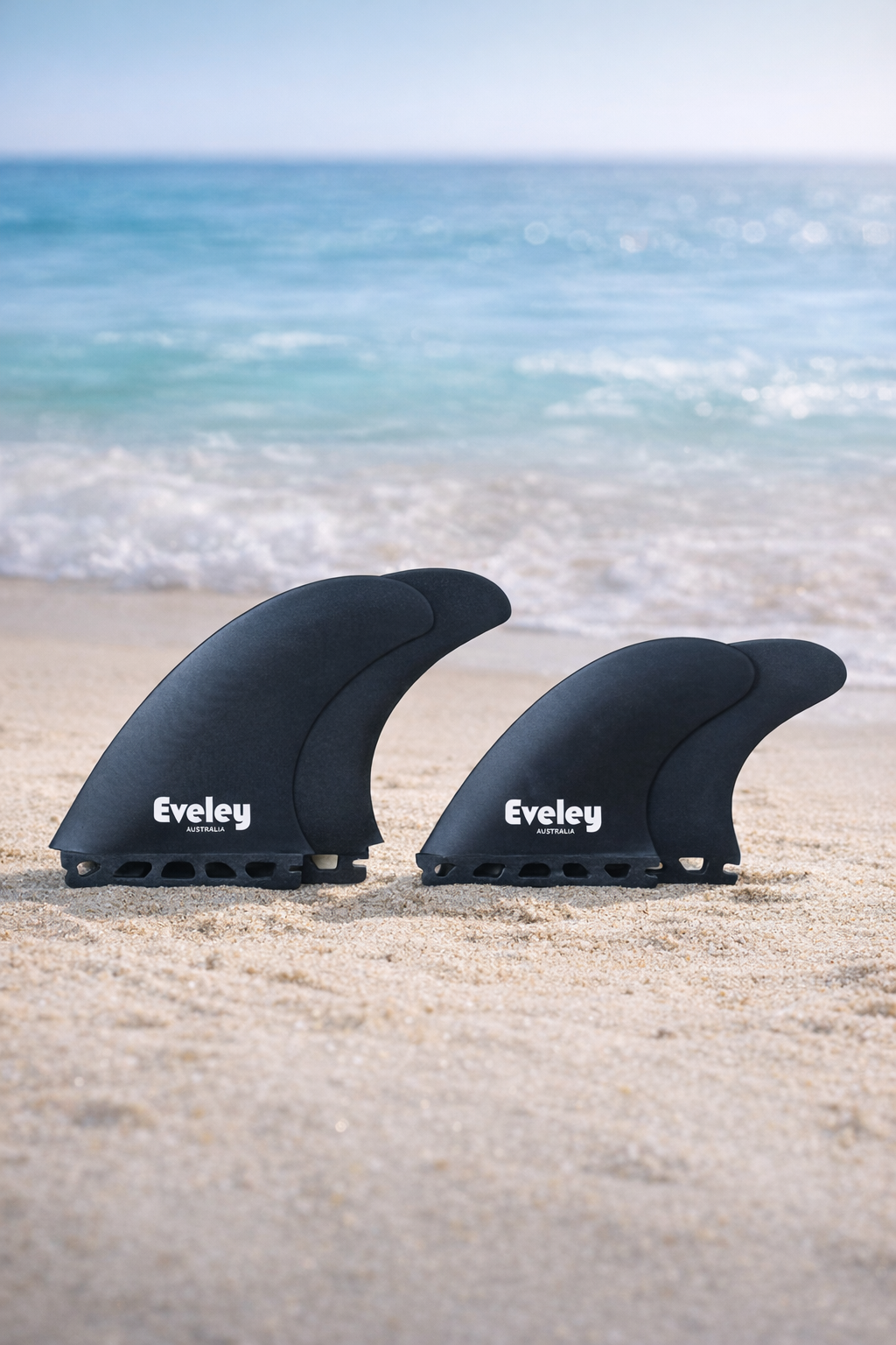 5.2 inch and 4.35 inch Big Boy quad surfboard fins in solid black Pro Glass, Futures compatible, set of four on a beach