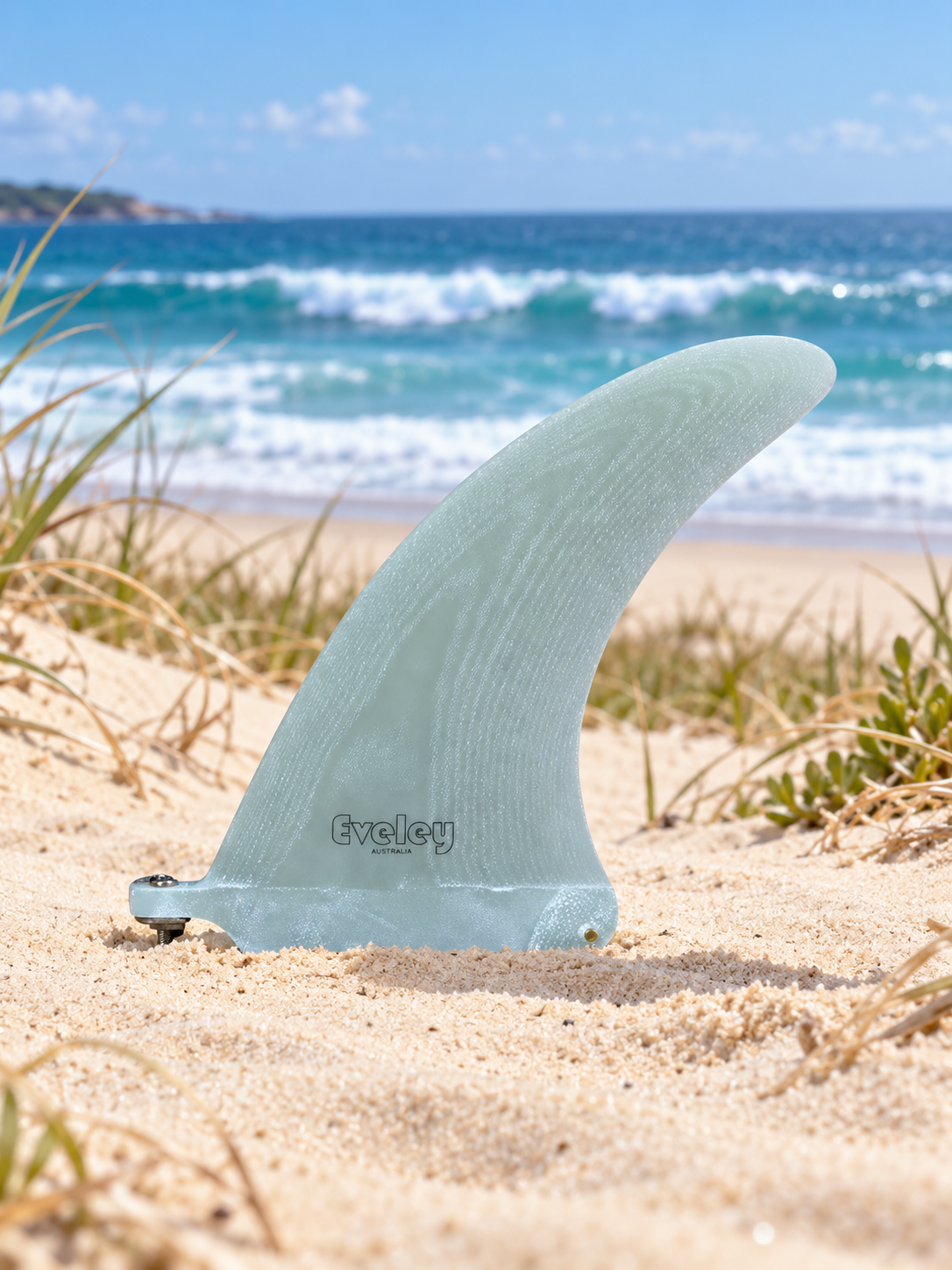 Eveley 7.25-inch Volan Pro Glass center fin standing on an Australian sand dune with a surf beach behind.