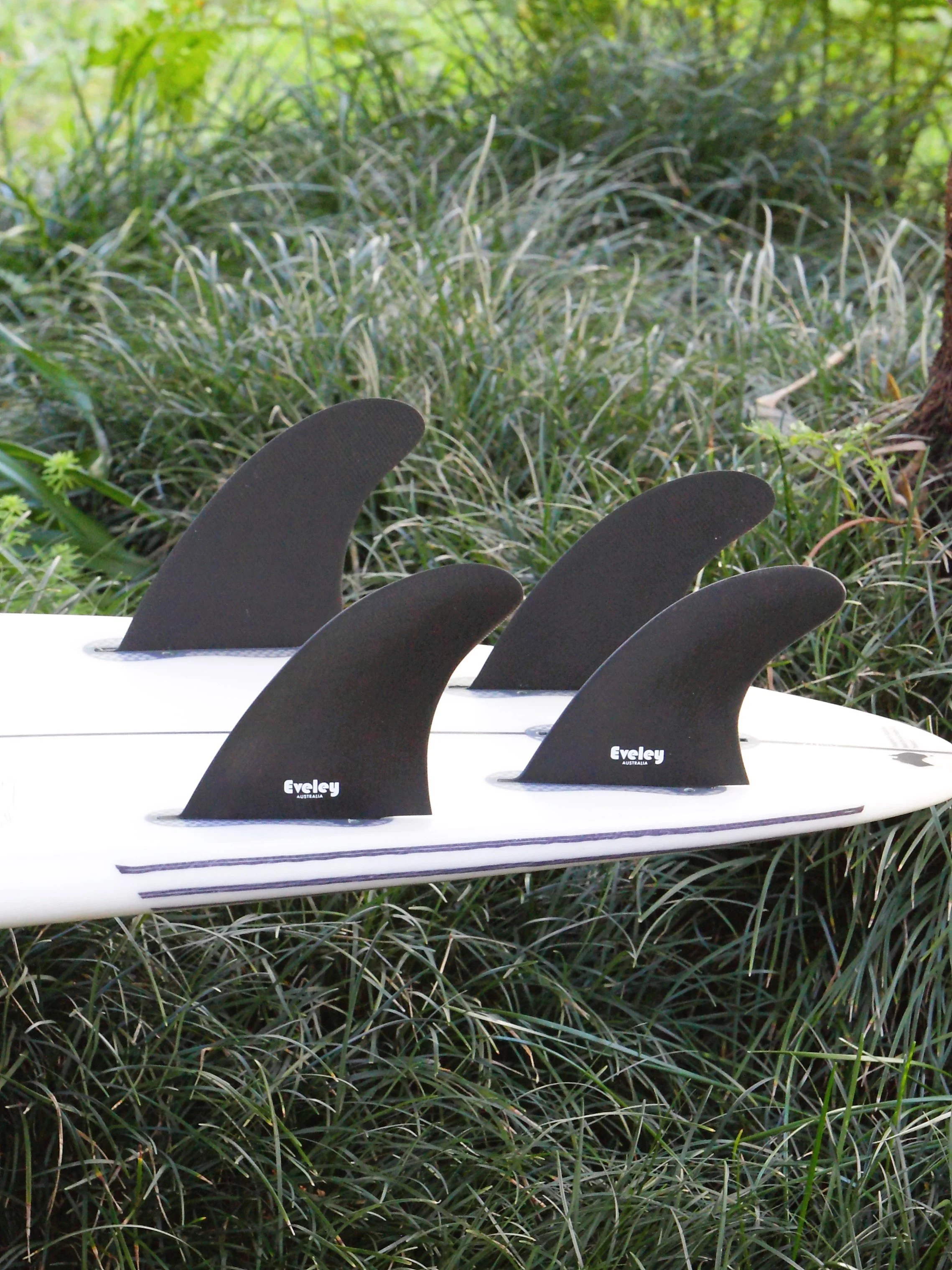 Set of four black Eveley Pro Glass quad surfboard fins with 4.7-inch front fins and 4.2-inch rear fins in FCSII fin plugs