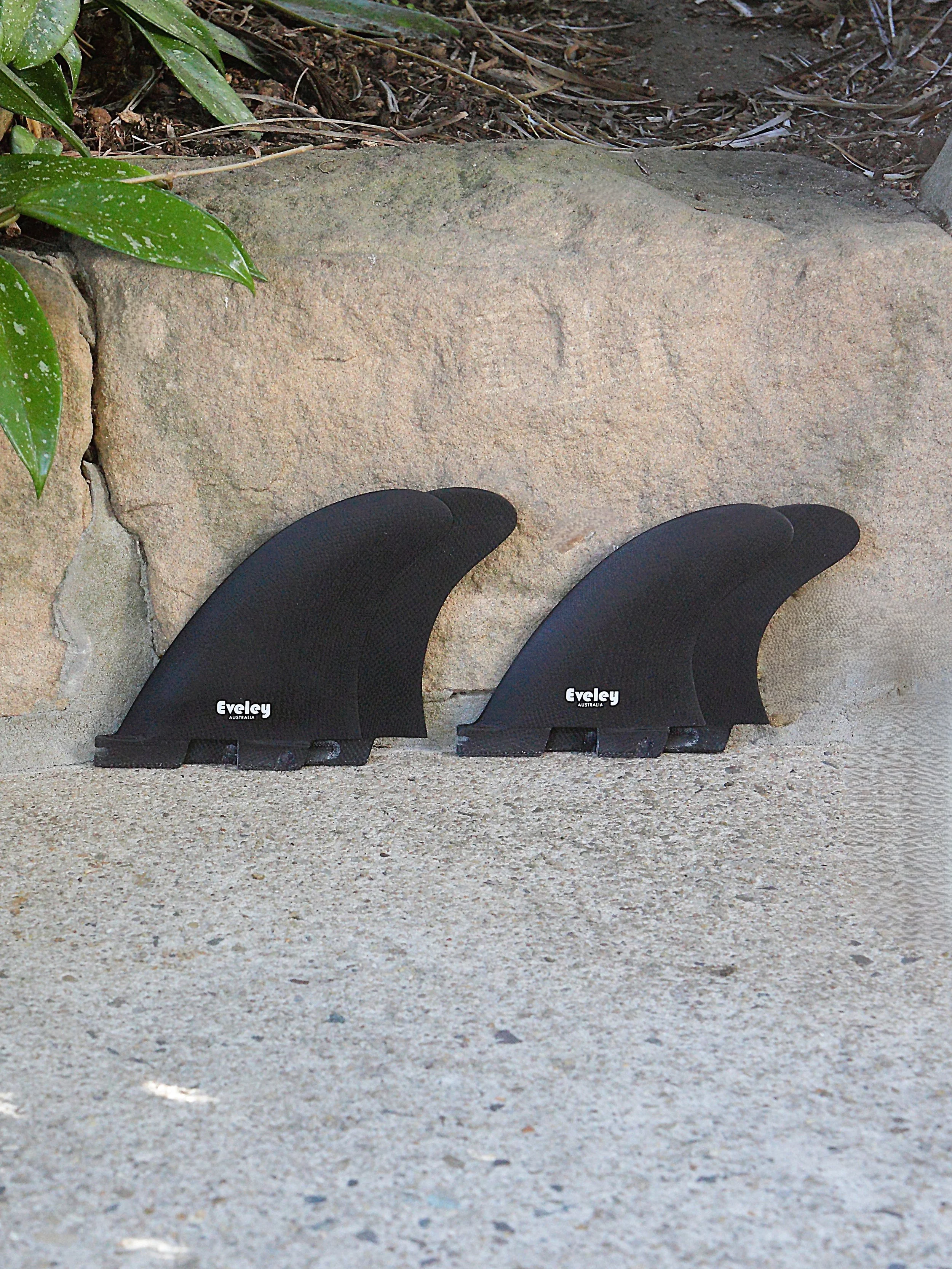 Black Eveley fins arranged as a four-fin FCSII compatible quad surfboard fin set