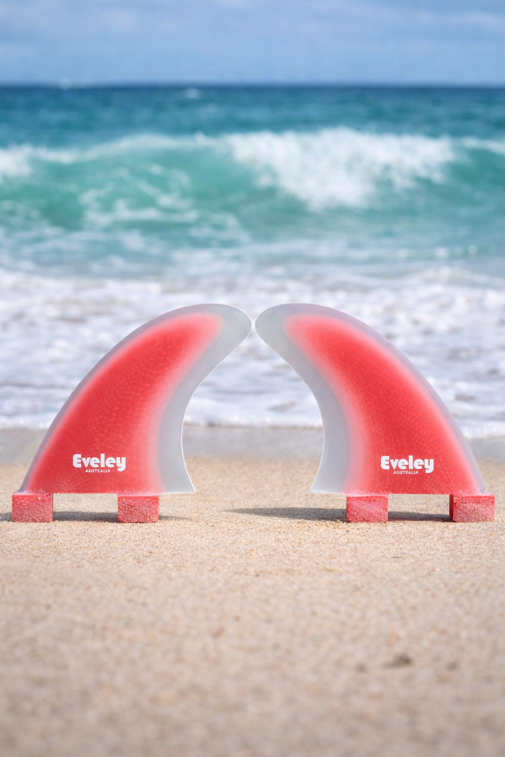 Red surfboard fins on sandy beach