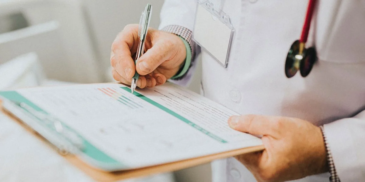Doctor Writing On Clipboard - Healthcare Continuous Improvement